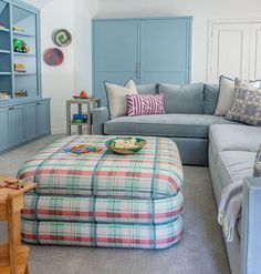 a living room filled with furniture and a large ottoman in front of a blue bookcase