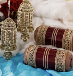 three bracelets with chains hanging from them on a blue cloth next to a rose