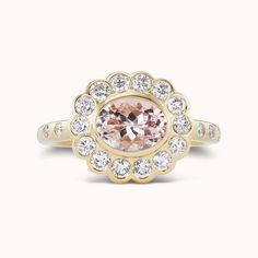 a ring with an oval shaped morganite surrounded by small white and clear stones in the center