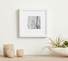 a white framed photograph sitting on top of a wooden table next to two vases