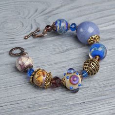 "This Lavender boho bracelet bracelet is a perfect gift for women. It's very tender and unique! This lampwork bracelet fits a 15.5-16.5cm (6.1\"-6.5\" inch) diameter wrist. If you need bigger or smaller size bracelet, please, write me the diameter of your wrist when making an order. Dimentions: 21cm. Materials: artist lampwork beads, metal and glass beads, metal fittings. Colors used: blue, lavender, lilac. Please, note, each lampwork bead is made by hand and may differ slightly. All the photos Bohemian Jewelry With Large Glass Beads, Bohemian Beaded Bracelets With Faceted Beads For Jewelry Making, Handmade Bohemian Glass Bracelets, Handmade Glass Bohemian Bracelets, Bohemian Crystal Bracelet With Large Beads For Gift, Bohemian Beaded Bracelet With Large Beads As Gift, Handmade Bohemian Glass Beaded Bracelets, Artisan Beaded Glass Bracelets, Bohemian Adjustable Glass Bracelets