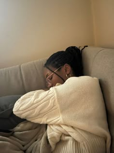 a woman laying on top of a couch covered in a blanket