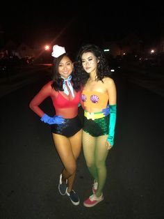 two women dressed up in costumes posing for the camera at night, with one woman standing next to her