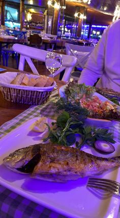 a person sitting at a table with plates of food in front of them and wine glasses on the side