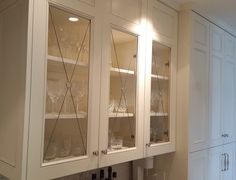 a kitchen with white cabinets and wine glasses on the glass front cabinet, along with an ice machine