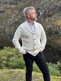 Mens Aran Buttoned Cardigan - Irish Cardigan - 100% Pure Merino Wool - Soft Wool - Natural White - Shawl Collar - HANDMADE IN IRELAND Elevate Your Wardrobe with our Men's Aran Buttoned Cardigan - A Classic Irish Essential Indulge in the timeless charm of Ireland with our meticulously handcrafted Men's Aran Buttoned Cardigan, a harmonious blend of classic design and modern comfort. This cardigan is a true masterpiece of Irish craftsmanship, combining traditional elements with contemporary flair. Irish Cardigans, Ruana Wrap, Irish Fashion, Buttoned Cardigan, White Shawl, Chunky Wool, Button Cardigan, V Neck Cardigan, Soft Wool