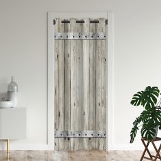 an open wooden door in a white room with a potted plant next to it