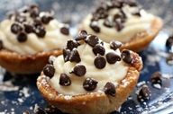 three desserts with chocolate chips and cream frosting on a blue plate covered in powdered sugar