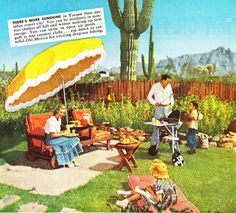 an old photo of people sitting in the grass with an umbrella and picnic table near by