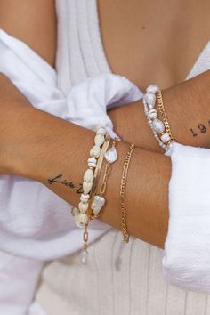 Flanked with natural white puka shells and pikake flowers, this unique shell bracelet evokes visions of Hawaii's white sands and soothing shores. Stack this gold bracelet with other beaded beauties and you'll be ready for your tropical escape.✦ DETAILS ✦✧ Name: Me'e (MAY aye) - Heroine.✧ Adjustable from 6.5"-8".✧ 6-7mm White Puka Shells.✧ Carved Resin Pikake Flowers.✧ 14kt Gold Filled with lobster clasp.✧ All Ke Aloha Jewelry pieces come packaged thoughtfully, beautifully, and ready for gift giv Beachy White Shell Bracelets, White Shell Beachy Bracelets, White Beachy Shell Bracelet, White Shell Beachy Bracelet, White Beaded Pearl Bracelet For Vacation, Bohemian White Pearl Bracelet For Beach, White Pearl Bracelet With Charm For Beach, White Shell Pearl Bracelet For The Beach, White Shell Pearl Bracelet For Beach