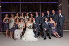 a large group of people in formal wear posing for a photo at a wedding party