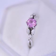 a pink diamond ring sitting on top of a white plate