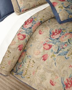 the comforter is made up with blue and pink flowers on it, along with two pillows