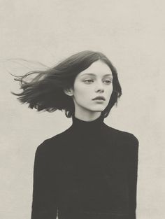 a black and white photo of a woman with her hair blowing in the wind