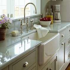 a bowl of fruit sitting on top of a kitchen counter next to a sink and coffee maker