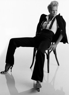 black and white photograph of a woman sitting on a chair with her legs crossed in the air