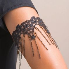 a woman's arm is covered in black lacy garter with chains hanging from it