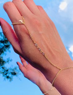 Our 18-karat gold-filled CZ hand chain with a moon charm is a beautiful and trendy piece of jewelry. This hand chain features a delicate chain that wraps around the wrist and connects to a ring, creating an elegant look. The moon charm adds a celestial touch, perfect for those who love astrology or simply appreciate the beauty of the night sky. Bracelet length:  6" + .5" Extension Finger Loop: 2.5"  Hand Chain Piece: 3.75" Material: 18 Karat Gold Filled, Hypoallergenic. Tarnish Resistant. Gold-filled does not de-laminate or peel like Gold plated Jewelry nor does it tarnish as readily as silver. Generally speaking, gold filled is better quality and will have a much longer lasting color than plated jewelry. Gold filled jewelry is an excellent option for those who wish to have a product of ex Resizable Yellow Gold Metal Jewelry, Gold Resizable Jewelry For Party, Delicate Adjustable Gold Body Jewelry, Adjustable Gold-tone Chain Jewelry, Dainty Chain Body Jewelry For Wedding, Adjustable 14k Gold Filled Jewelry For Party, Delicate Gold Rings For Party, Dainty Resizable Rose Gold Jewelry, Adjustable Delicate Chain Body Jewelry For Wedding