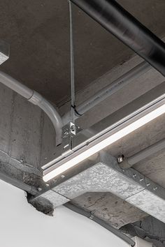 an overhead view of a light fixture in a room with concrete walls and ceiling beams