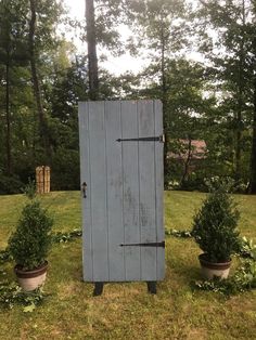 an old outhouse in the middle of some bushes and potted plants on the lawn