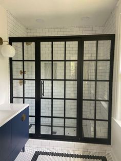 a bathroom with black and white tile flooring next to a walk in shower door