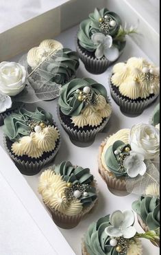 cupcakes decorated with green and white flowers in a box