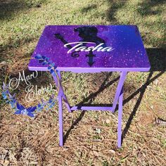 a purple table sitting on top of a grass covered field next to a tree with the word faith painted on it