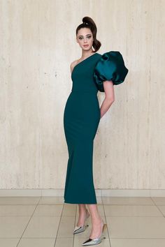 The Greta Constantine Amaryllis Dress features a striking asymmetrical neckline with an exaggerated flourish sleeve, creating a bold yet elegant look. This A-line gown balances a sleek silhouette with a dramatic statement sleeve, making it a standout choice for formal events and galas. True to size 68% polyamide | 32% elastane body Made in Toronto | Fabric milled in Italy Dry Clean *Note that Special Order pieces take 22 - 26 weeks to ship. Formal Gown With Draped Sleeves And Asymmetrical Neckline, Voluminous Gown For Gala, One-shoulder Gown With Draped Sleeves, Voluminous Draped Sleeve Party Dress, Party Dress With Voluminous Draped Sleeves, Voluminous Party Dress With Draped Sleeves, Chic Gown With Asymmetrical Neckline And Fitted Bodice, Elegant Voluminous Evening Midi Dress, Elegant Voluminous Party Gown