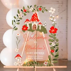 a baby shower sign with flowers and mushrooms on it in front of balloons that say welcome to mardene's