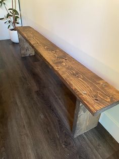 a wooden bench sitting next to a potted plant on top of a hard wood floor