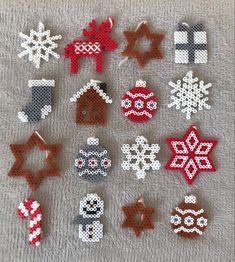 christmas ornaments made out of perler beads on a gray surface with white and red snowflakes