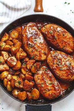 chicken and potatoes in a skillet with a wooden spatula on the side, ready to be eaten