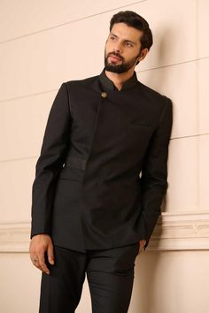 Black bandhgala in a premium suiting fabric featuring an overlapping front panel and novelty buttons, with a textured collar. Comes with a cotton-satin formal shirt and Jodhpuri trouser.
Components: 3
Pattern: Textured
Type Of Work: Linear Patterns
Neckline: Stand Collar
Sleeve Type: Straight Full
Fabric: Bandhgala : Suiting Fabric, Shirt : Cotton Satin, Trousers : Suiting Fabric
Color: Black
Other Details: 
Linear pattern textures
Overlapped panel
Novelty buttons
Occasion: 
Cocktail and Recepti