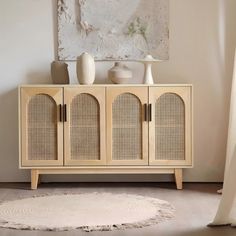 a room with a white rug and a wooden cabinet in the corner that has two vases on top of it