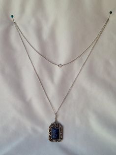 Featuring a vintage circa 1970s Sarah Coventry 'Roman Holiday' necklace, this piece showcases a SilverTone chain with a spring ring closure, intricate silver work, and silver crosses on the metal sections. The pendant boasts an ornate, mottled blue swirl design, mimicking faux blue sodalite cabochon. Styled in the Edwardian fashion.   It is preowned yet remains in exquisite condition.  The necklace measures 24 inches in length, while the pendant is 1 inch wide by 1 3/4 inches tall. For further details on this item, please examine all photos and feel free to message me with any inquiries. After Purchase, If the item is not what you expected, please let me know if there is anything wrong with your item so that I can promptly resolve the issue and ensure your satisfaction.   Don't forget to F Vintage Hallmarked Blue Jewelry, Vintage Blue Hallmarked Jewelry, Vintage Blue Cabochon Jewelry, Blue Vintage Cabochon Jewelry, Ornate Sterling Silver Necklace With Vintage Charm, Ornate Silver Cabochon Necklace, Ornate Silver Necklace With Cabochon, Vintage Silver Necklace With Vintage Charm, Victorian Silver Necklace With Cabochon