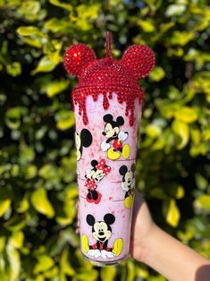 a person holding up a glass with minnie mouse on it