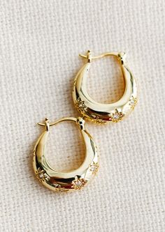 A pair of oblong oval hoops in gold with clear star shaped crystal detailing. Chunky Gold Earrings, Bridesmaids Jewelry, Earrings Gold Hoop, Holiday 2024, Chunky Hoop Earrings, Jewelry Lookbook, Gold Filled Earrings, Star Studs, Christmas 2024