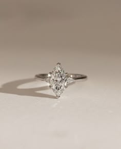 an engagement ring with a pear shaped diamond in the center on a white surface,