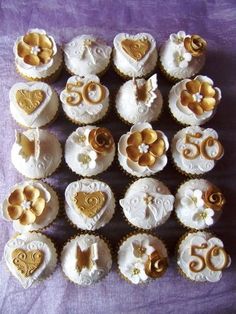 cupcakes decorated with gold and white icing on a purple tablecloth,