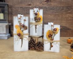 four wooden blocks decorated with pine cones, acorns and dried berries tied to twine