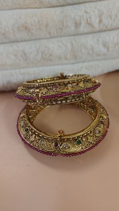 Jadau pure brass gold plated multicolor kundan stones bangles | Broad Bangles - Free Delivery In Personal trust me this is so much beautiful and in great quality, video call also available too see our products. Adorn your wrist with the exquisite beauty of our Gold Kundan Ruby Bangle, a stunning piece of handcrafted Indian jewelry that exudes elegance and charm. This timeless bangle features intricate Kundan work embellished with radiant ruby stones, creating a captivating fusion of traditional and contemporary design. Perfect for special occasions such as weddings, festivals, and celebrations, our gold Kundan bangle is a must-have accessory for every discerning woman. The rich hues of gold and ruby add a touch of luxury and sophistication to any ensemble, making it a versatile statement p Luxury Exquisite Wedding Bangle, Pink Kundan Bangle For Festivals, Diwali Temple Jewelry Jeweled Bracelets, Pink Kundan Bangle For Gift, Festive Jeweled Kundan Bracelets, Kundan Jeweled Bracelets For Diwali, Traditional Gold Plated Bangle For Celebrations, Gold Jeweled Bangle For Celebration, Pink Kundan Bangle For Festive Occasions