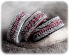 three red and silver bracelets sitting on top of a metal banana peel in front of a white background