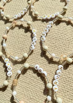 several white beads with words on them sitting on a cloth covered floor next to a pair of scissors