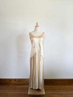 a dress on a mannequin in front of a white wall and wooden floor