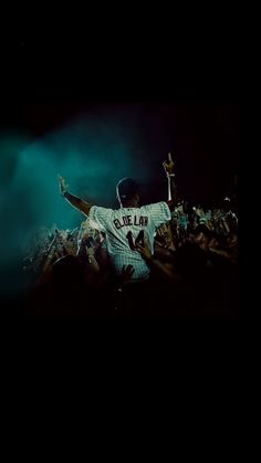 a baseball player with his arms up in the air and fans behind him at night