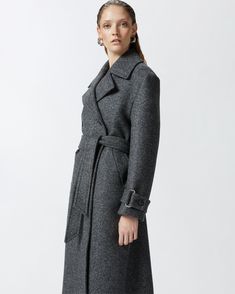 Women's long double-breasted coat made from yarn-dyed wool-blend twill cloth. The silhouette—which includes a lapel collar, long sleeves with cuff tab and matching-fabric waist belt—is inspired by the classic trench coat. Slanted side pockets and double-breasted button fastening. Luxury Wool Coat With Belted Cuffs For Office, Belted Wool Coat With Notch Lapel, Formal Double-breasted Wool Coat With Belted Cuffs, Formal Wool Coat With Belted Cuffs And Notch Lapel, Formal Wool Coat With Belted Cuffs And Lapel Collar, Formal Long Wool Coat With Belted Cuffs, Luxury Wool Belted Outerwear, Luxury Wool Coat With Double Button For Fall, Luxury Wool Coat With Double Button Closure For Fall