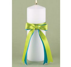 a white candle with a green ribbon around it