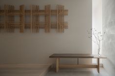 a wooden bench sitting in front of a white wall