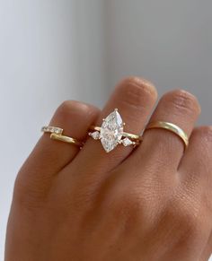 a woman's hand with two gold rings on it and a diamond ring in the middle