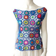 a mannequin wearing a blue top with multicolored crocheted flowers